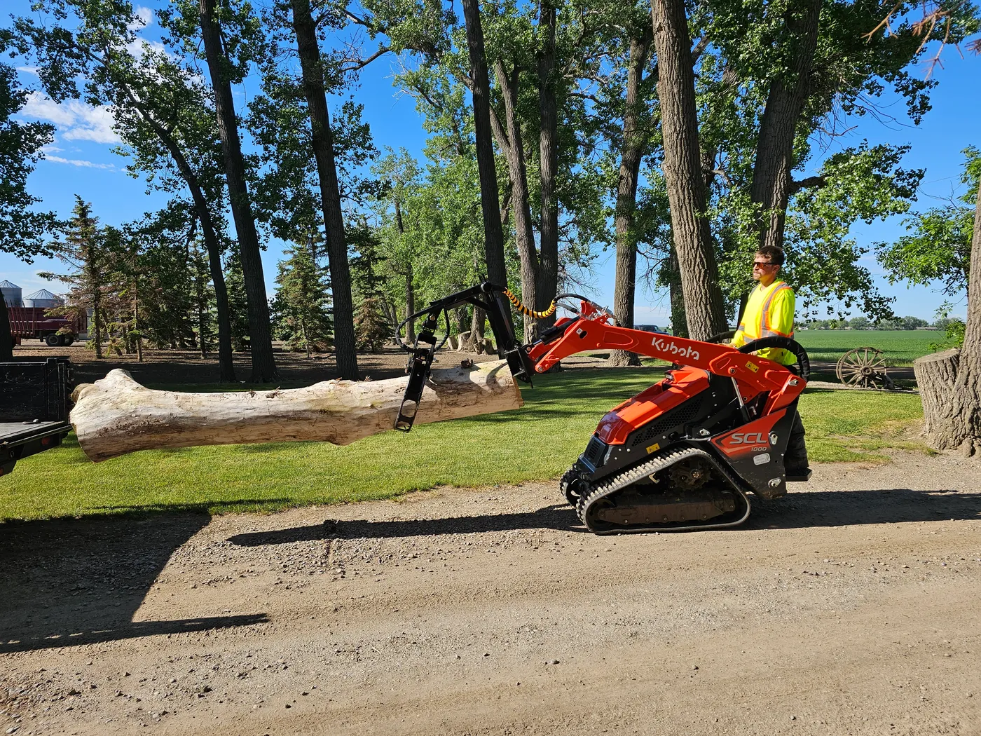 Compact tracked loader moving timber across a cleared work area
