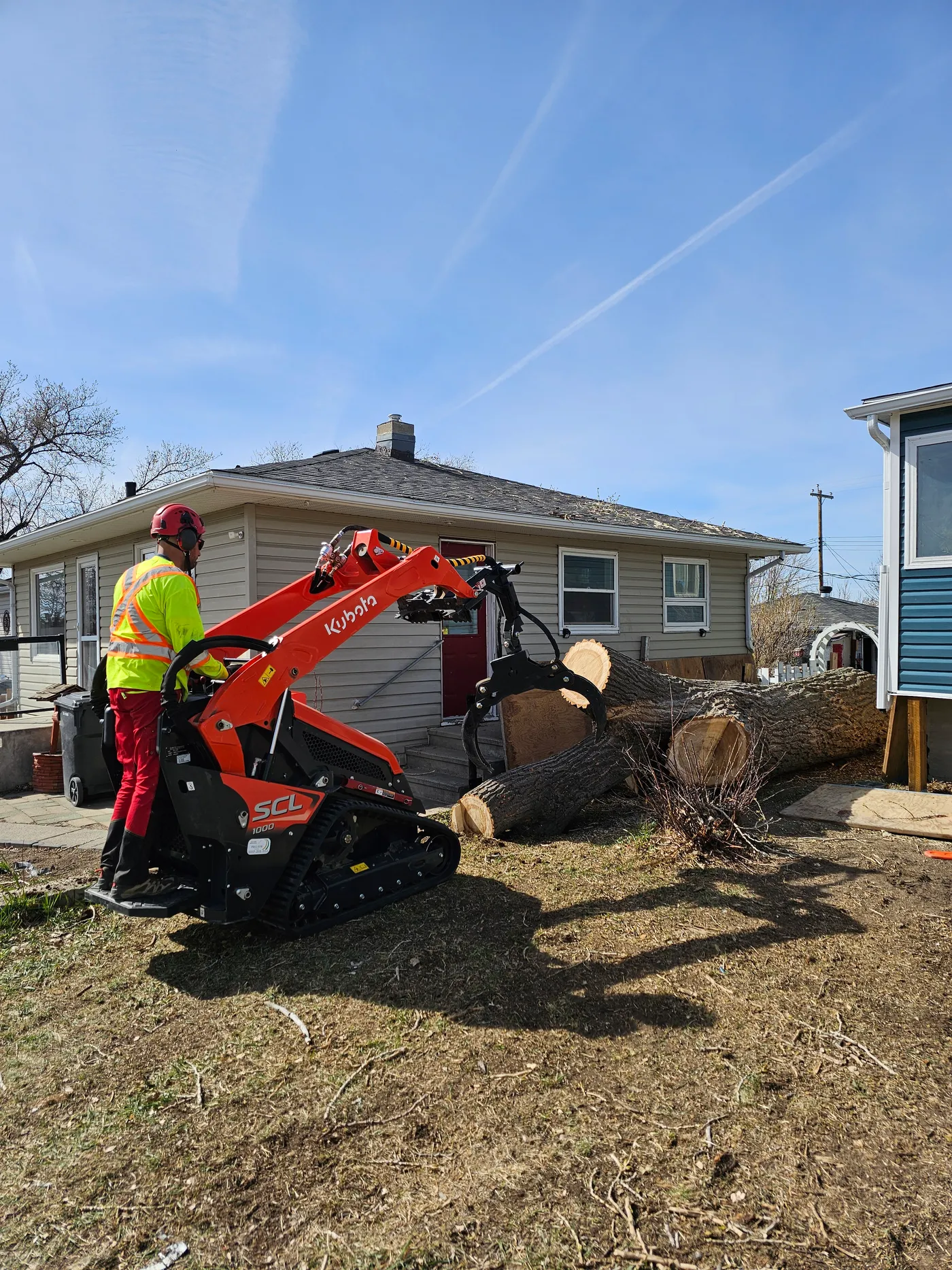 Tree crew and compact loader handling a large trunk section